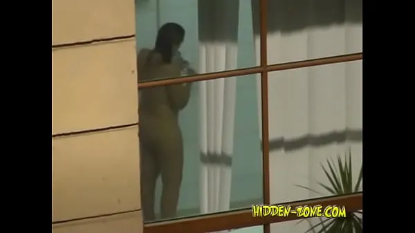 A girl washes in the shower, and we see her through the window Video baru yang besar