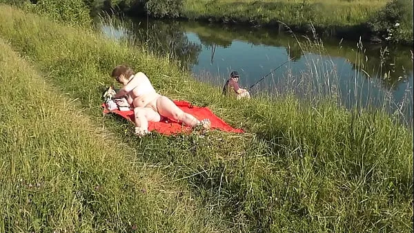 Grote MILF sexy Frina on river bank undressed and sunbathes naked. Random man fisherman watching for her, and in the end decided to join naked woman. Wild beach. Nudist beach. Public nudity. Public exposure. Naked in public nieuwe video's
